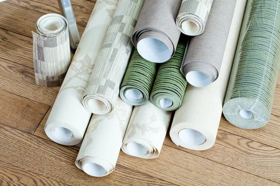 Rouleaux de papier peint décoratif disposés sur parquet en bois