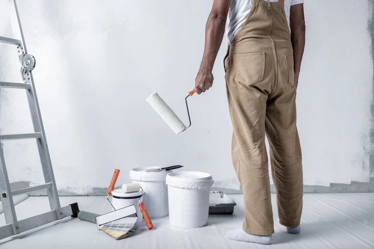 Scène intérieure sur surface blanche avec pot de peinture ouvert contenant peinture bleue mélangée, bâtonnet mélangeur bois inséré